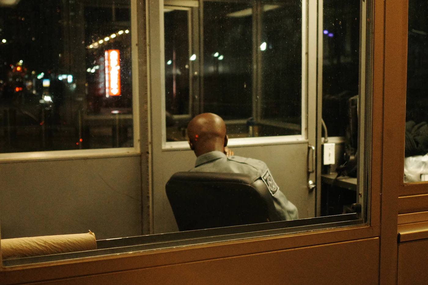 Security officer at a night post, seen through a window
